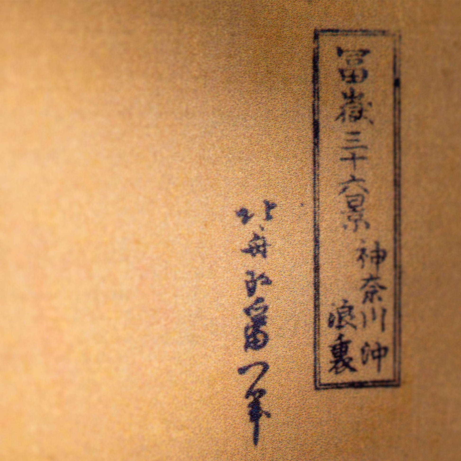 Close-up of black ink Japanese calligraphy on textured beige paper with vertical text lines and bordered characters, inspired by the classic Hokusai Tide Art Clock design.