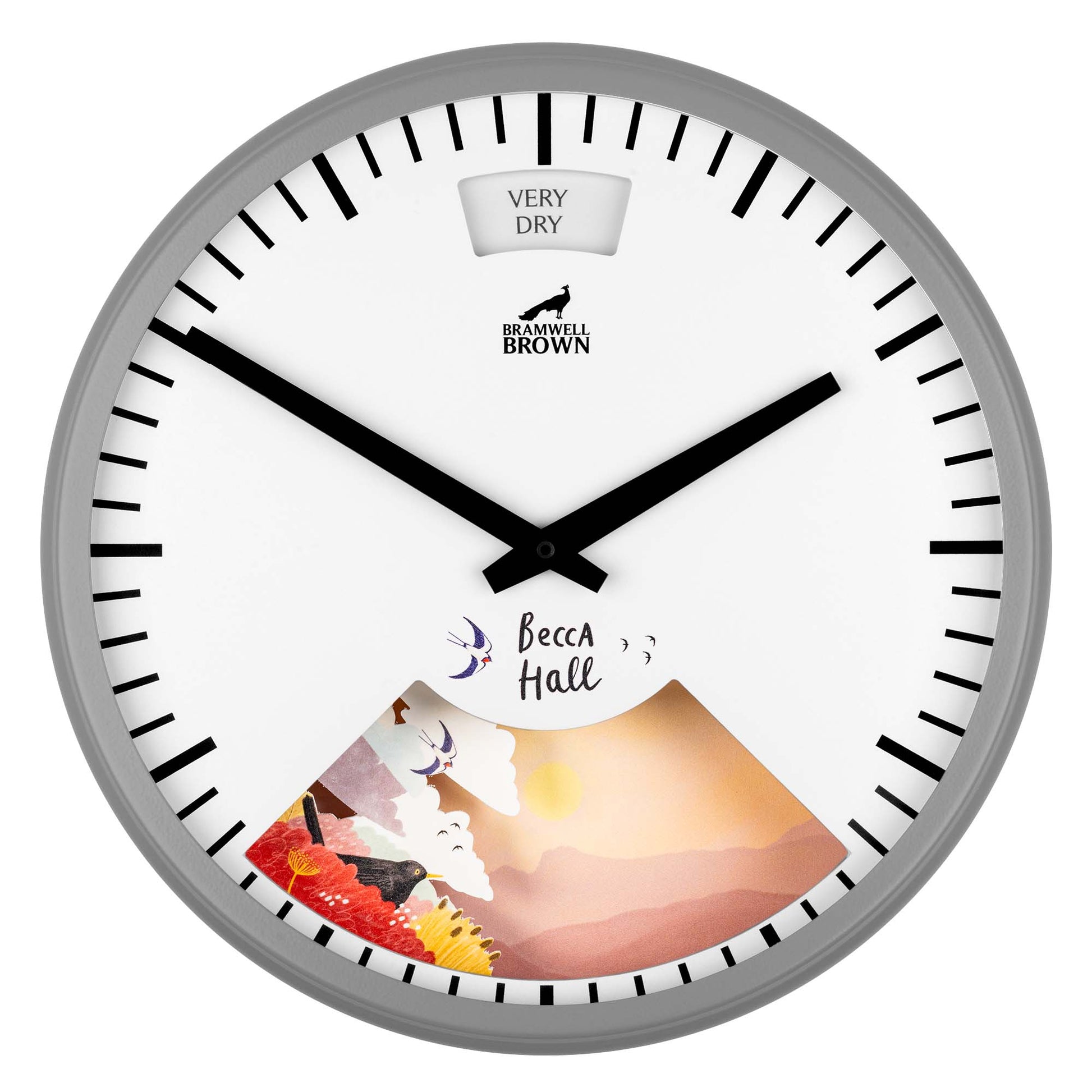 A round wall clock with black hour and minute hands, black tick marks, and a section showing an illustrated landscape with flowers and mountains. The top of the clock reads VERY DRY and Bramwell Brown.