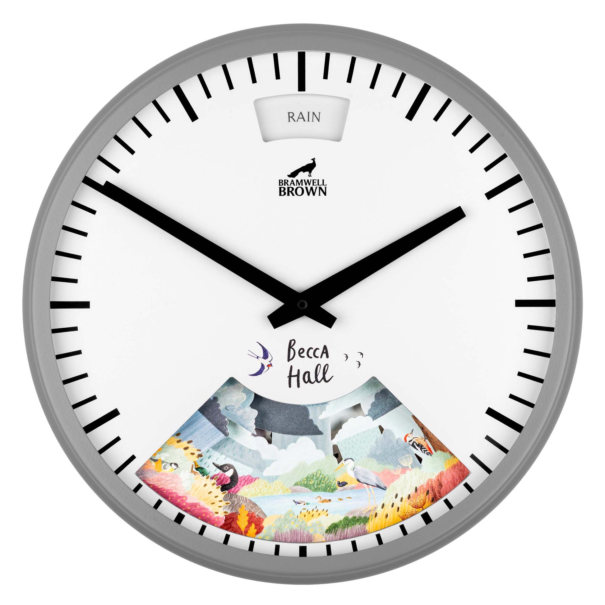 A round wall clock with black hour and minute hands on a white face, labeled Bramwell Brown. The top says RAIN, and the lower part features colorful illustrated scenery with Becca Hall written above it.