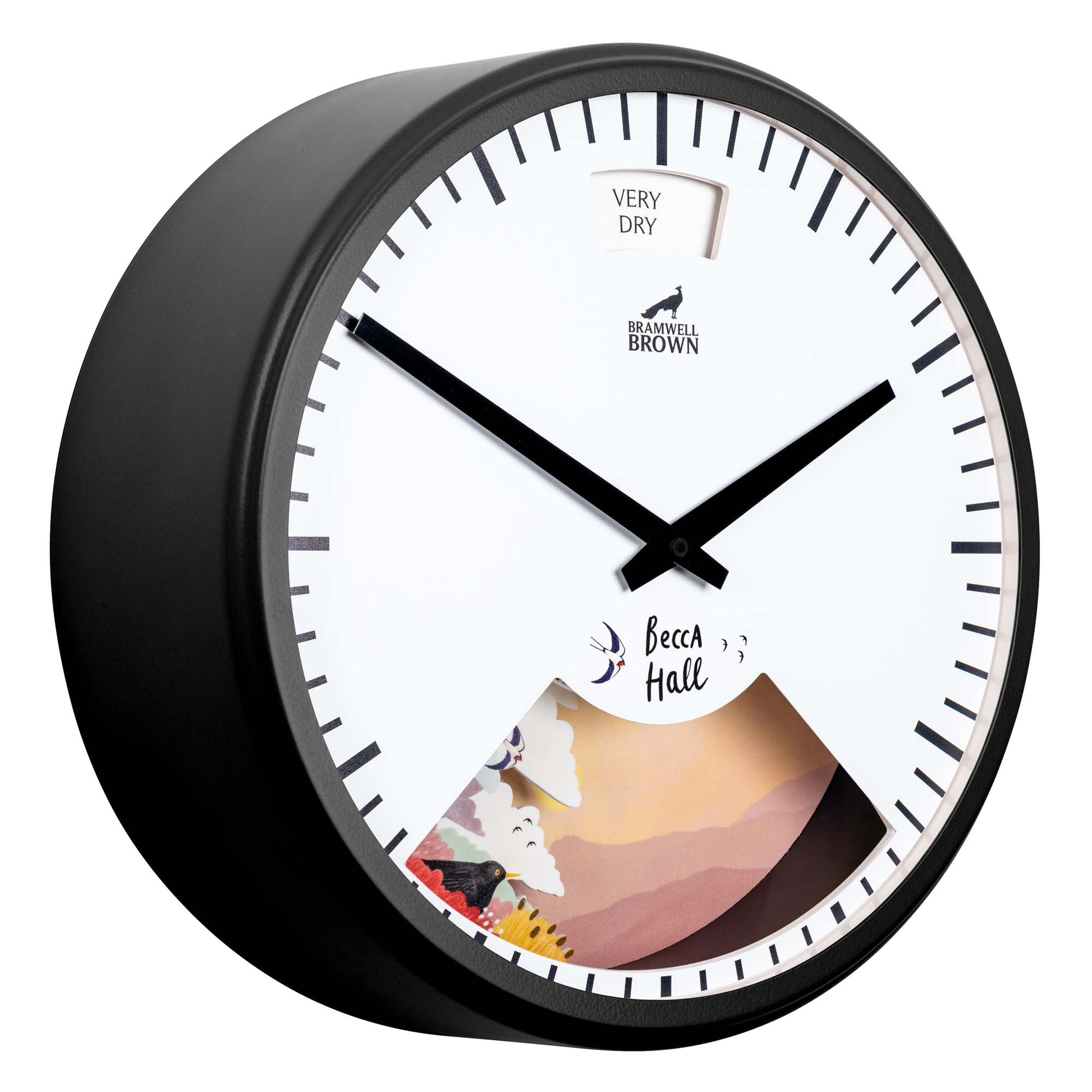 A round wall clock with a white face, black frame, and black hands. The lower part has a colorful weather-themed illustration, and a small gauge at the top reads “Very Dry.” The clock face also displays Bramwell Brown and Becca Hall.