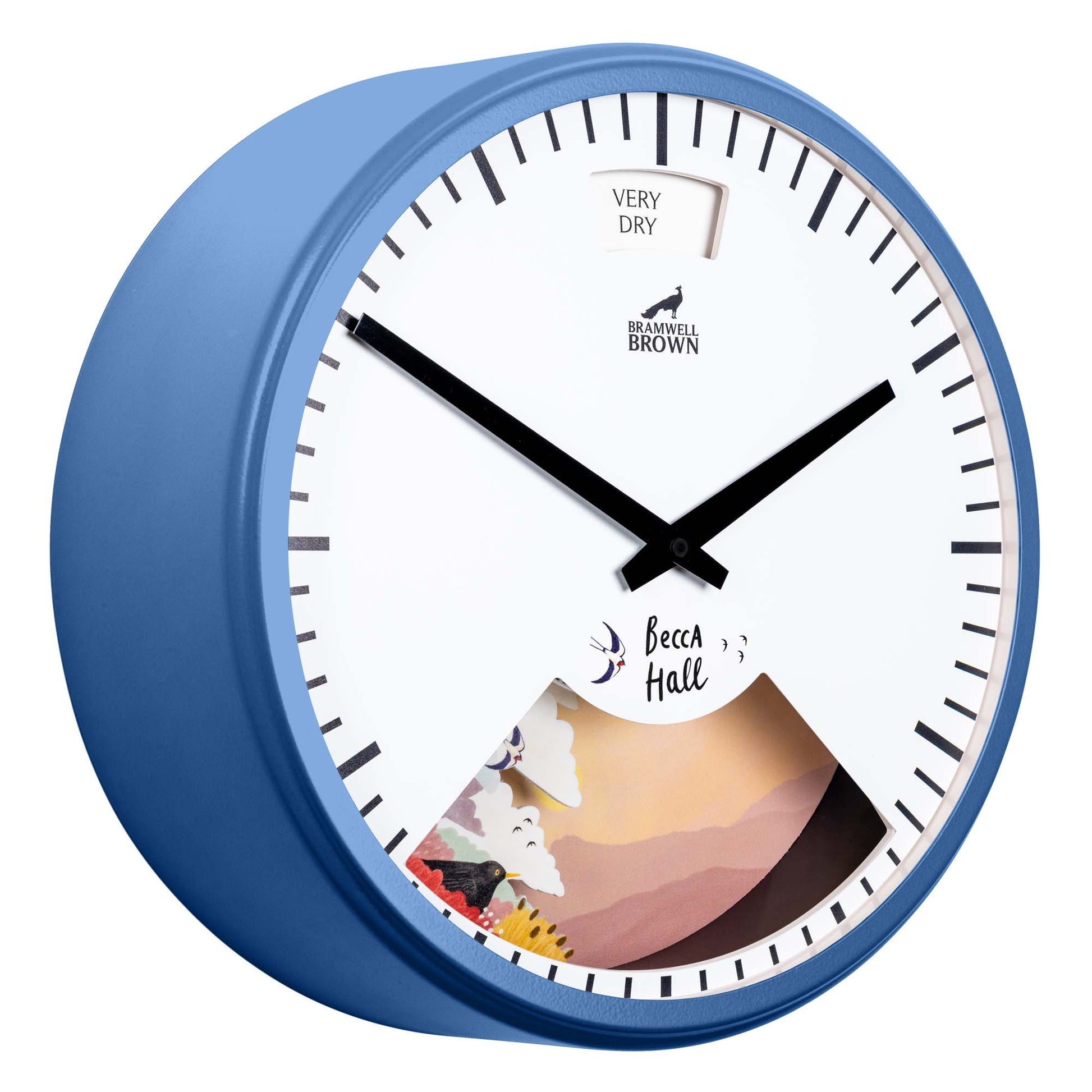 A blue-framed wall clock with black hands and minimal markings. The top shows a VERY DRY label, and the lower section features colorful artwork and the text Becca Hall.