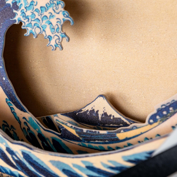 Close-up of the Hokusai Tide Art Clock, showcasing layered artwork inspired by The Great Wave Off Kanagawa with stylized blue waves on a beige background.