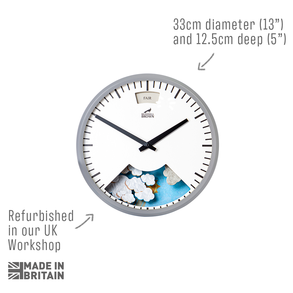A round wall clock with a grey frame, white face, and black hands. The lower part of the clock displays a weather illustration. Text indicates the clock is 33cm in diameter, 12.5cm deep, and refurbished in the UK.