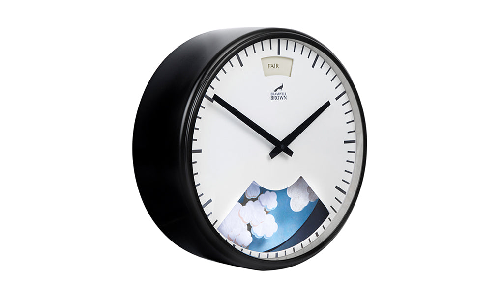 A round wall clock with a black frame, simple black hands, and a white face. The lower part displays an illustration of clouds, and a small window at the top shows the word FAIR with a bird icon and BRUIN BROWN text below.