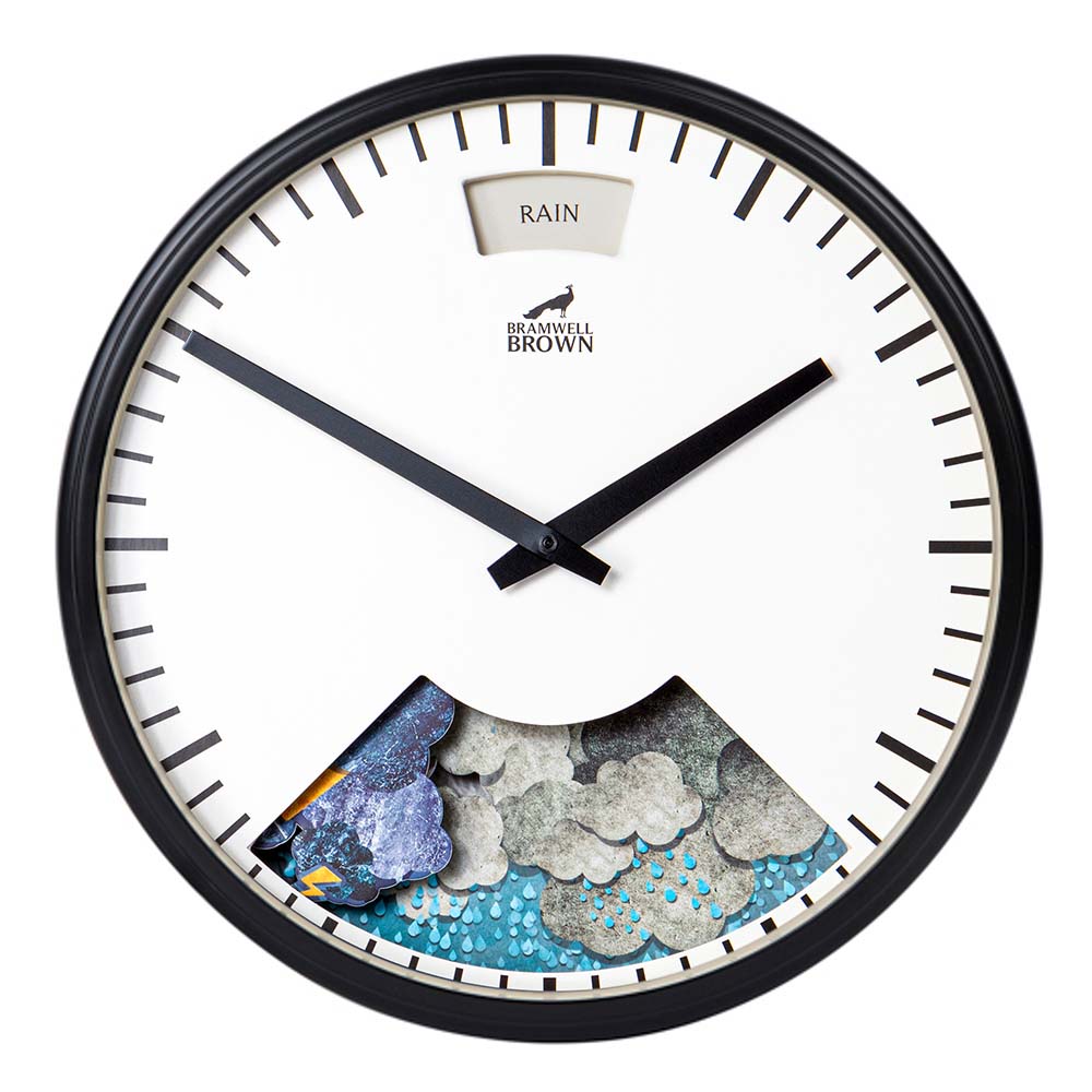 A round wall clock with black frame and hands, minimal black markers, and a display window showing animated clouds and raindrops. A small window at the top reads RAIN. The clock brand is Bramwell Brown.